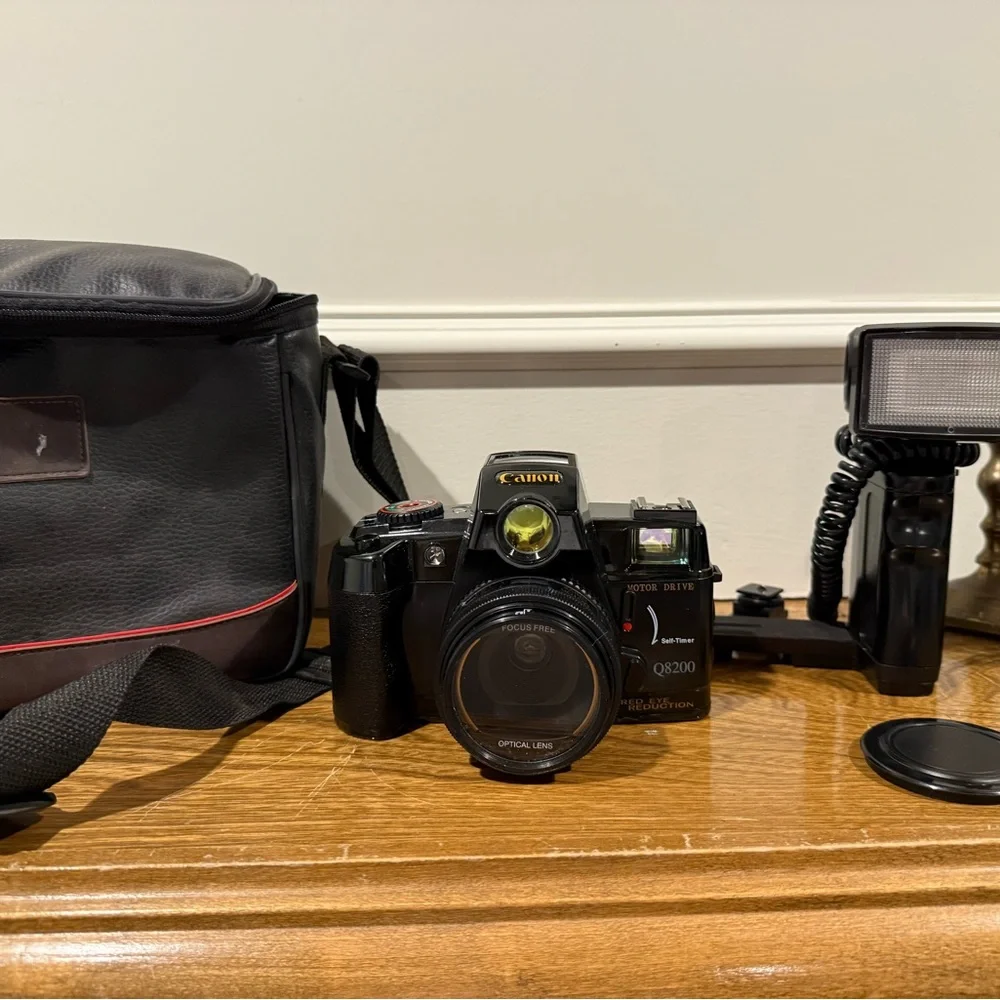Vintage Canon camera with a flash attachment and carrying case.
